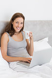 Relaxed young woman using laptop in bed