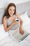 Relaxed young woman using laptop in bed