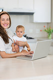 Smiling mother with baby using laptop