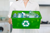 Mid section of woman carrying box with recycling symbol