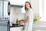 Smiling young woman preparing food in kitchen