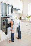Rear view of woman looking into the oven in kitchen
