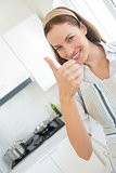 Smiling young woman gesturing thumbs up in kitchen