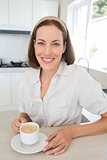 Smiling woman with coffee cup in kitchen
