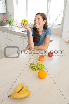 Smiling woman with fruits on counter in kitchen