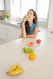 Woman eating apple with fruits on kitchen counter