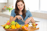 Portrait of a woman cutting fruits in kitchen