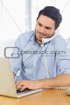 Businessman using laptop and telephone