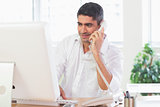 Businessman using computer and telephone