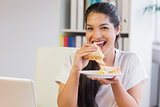 Happy businesswoman eating sandwich