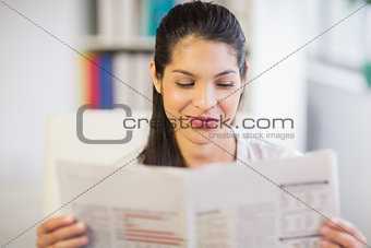 Young businesswoman reading newspaper