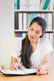 Businesswoman writing notes in diary