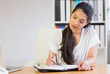 Young businesswoman writing in diary