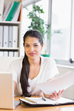 Businesswoman holding documents at desk