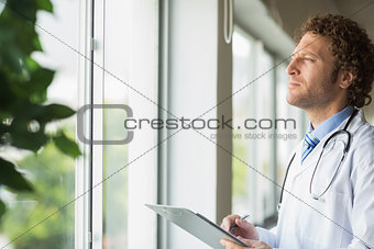 Thoughtful doctor with clipboard