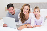 Family with laptop in bed