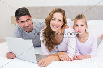 Family with laptop in bed
