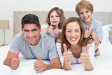 Family gesturing thumbs up in bed