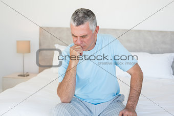 Pensive senior man sitting on bed