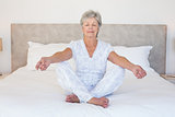 Senior woman meditating in bed