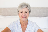 Happy senior woman sitting on bed