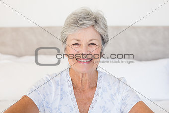 Happy senior woman sitting on bed