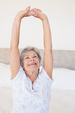 Senior woman stretching on bed