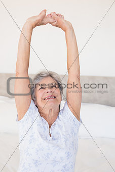 Senior woman stretching on bed