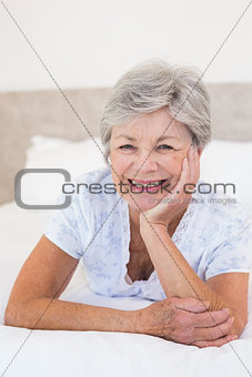 Happy senior woman lying in bed