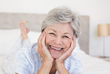 Senior woman with head in hands on bed