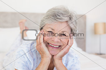 Senior woman with head in hands on bed