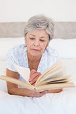 Senior woman reading story book in bed