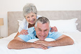 Senior woman lying on husband in bedroom
