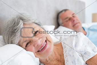 Senior woman lying on bed with man