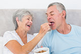 Loving senior woman feeding cereals to husband