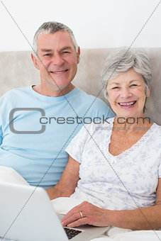 Senior couple with laptop in bed