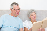 Senior couple reading book together in bed