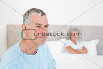 Sad senior man with woman in background