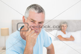 Thoughtful senior man with woman in background