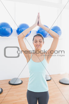 Sporty woman with joined hands in fitness studio