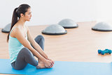 Fit woman doing butterfly stretch in exercise room