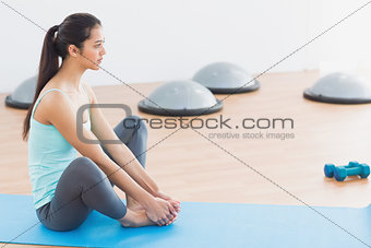 Fit woman doing butterfly stretch in exercise room