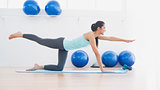 Sporty woman stretching hand and leg in fitness studio