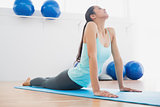 Fit young woman doing the cobra pose in fitness studio