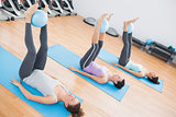 Sporty women holding balls between ankles in fitness studio