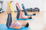 Sporty young women with exercise bands in fitness studio