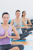 Women in Namaste position with eyes closed at fitness studio