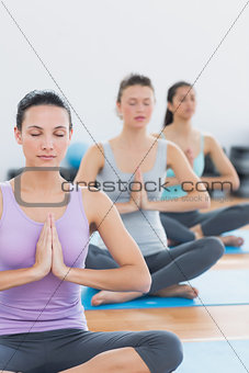 Women in Namaste position with eyes closed at fitness studio