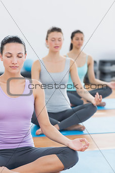 Women in lotus posture with eyes closed at fitness studio