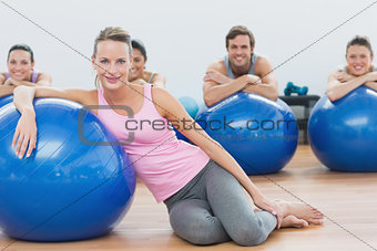 Instructor and class with exercise balls sitting at fitness studio